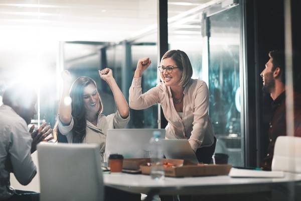 Employee onboarding - Shot of colleagues celebrating during a meeting in a modern office